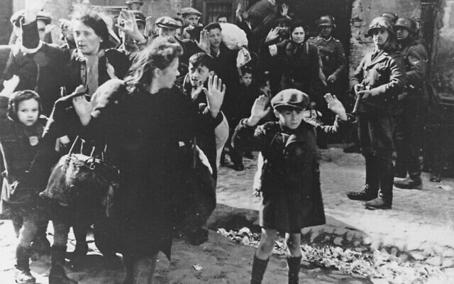 Un groupe de Juifs, dont un petit garçon, est escorté hors du ghetto de Varsovie par des soldats allemands, le 19 avril 1943. (Crédit : Domaine public)