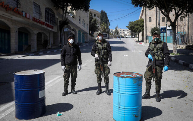 Les forces de sécurité palestiniennes portant des masques bloquent l'entrée de la ville de Bethléem en Cisjordanie, le 8 mars 2020. (Wisam Hashlamoun/Flash90) Les forces de sécurité palestiniennes portant des masques bloquent l'entrée de la ville de Bethléem en Cisjordanie, le 8 mars 2020. (Wisam Hashlamoun/Flash90)