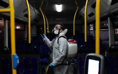 Des agents en tenue de protection désinfectent un bus à titre préventif afin de lutter contre la propagation du coronavirus, à Tel Aviv, le 9 mars 2020. (Crédit : Tomer Neuberg / Flash90)