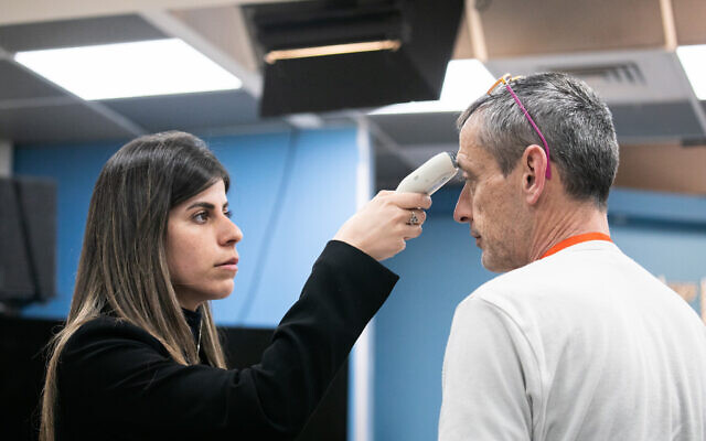 Un homme soumis à un test de fièvre à son arrivée pour la conférence de presse du Premier ministre Benjamin Netanyahu au bureau du Premier ministre à Jérusalem, le 12 mars 2020. (Olivier Fitoussi/Flash90)