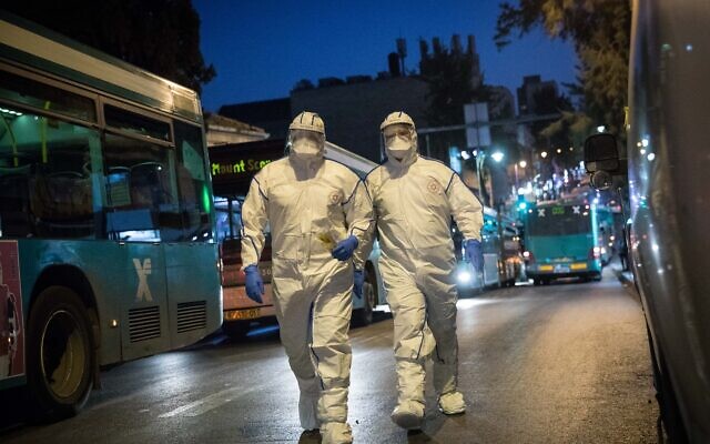 Des secouristes du Magen David Adom portant une tenue de protection contre le nouveau coronavirus arrivent pour tester un patient présentant des symptômes de Covid-19, à Jérusalem, le 16 mars 2020. (Crédit : Yonatan Sindel/Flash90)