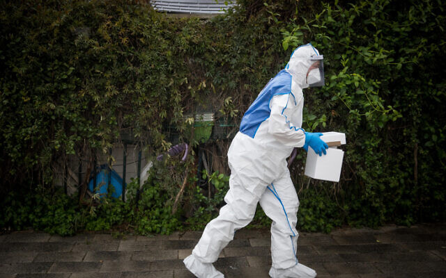 Un secouriste du Magen David Adom portant une tenue de protection contre le coronavirus arrive pour tester un patient présentant des symptômes de Covid-19, à Jérusalem, le 16 mars 2020. (Crédit : Yonatan Sindel/Flash90)