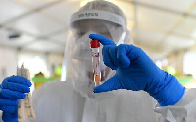 Un employé du Magen David Adom sur un site de drive-in pour collecter des échantillons en vue de tests de coronavirus, Tel-Aviv, 20 mars 2020. (Tomer Neuberg/Flash90)