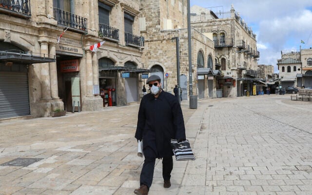 Un homme portant un masque facial par crainte du coronavirus à proximité de la porte de Jaffa, dans la Vieille Ville de Jérusalem, le 21 mars 2020 (Crédit : Yossi Zamir/Flash90) Un homme portant un masque facial par crainte du coronavirus à proximité de la porte de Jaffa, dans la Vieille Ville de Jérusalem, le 21 mars 2020 (Crédit : Yossi Zamir/Flash90)