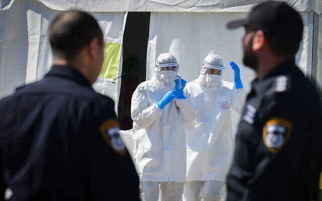 Des membres de l'équipe médicale du Magen David Adom, portant des équipements de protection, manipulent un échantillon de coronavirus sur un site de drive-in pour le tester à Tel Aviv, le 22 mars 2020. (Flash90)