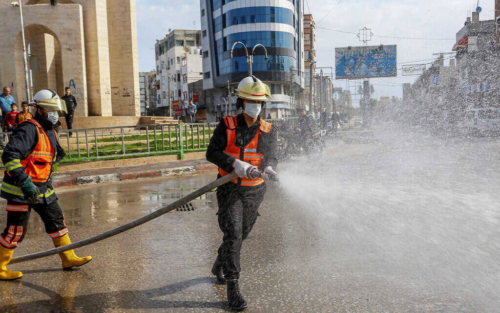 Des agents de la défense civile palestinienne désinfectent une rue à Rafah, dans le sud de la bande de Gaza, le 23 mars 2020, après que les deux premiers cas de coronavirus à Gaza ont été confirmés. (Crédit : Abed Rahim Khatib/Flash90)