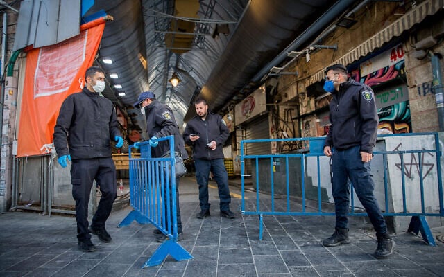 Des employés de la municipalité de Jérusalem ferment les entrées du marché  Mahane Yehuda à Jérusalem, le 24 mars 2020 (Crédit : Yonatan Sindel/Flash90)