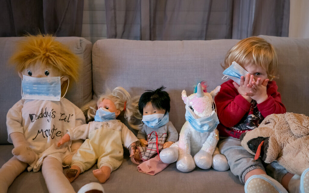 Des enfants, confinés à cause du coronavirus, jouent à mettre des masques sur leurs animaux en peluche, le 29 mars 2020. (Crédit : Chen Leopold/Flash90)