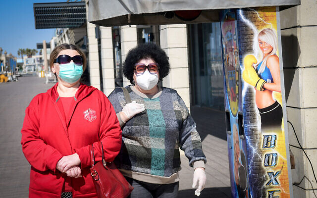 Deux femmes portent un masque le long de la promenade d'Ashkelon, en bord de mer, le 29 mars 2020 (Crédit : Flash90)