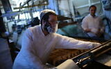 Un juif orthodoxe portant un masque facial comme mesure préventive contre le coronavirus prépare des matzot pour Pessah à l'usine Matzot Aviv à Bnei Brak, le 30 mars 2020. (Crédit : Tomer Neuberg/Flash90)