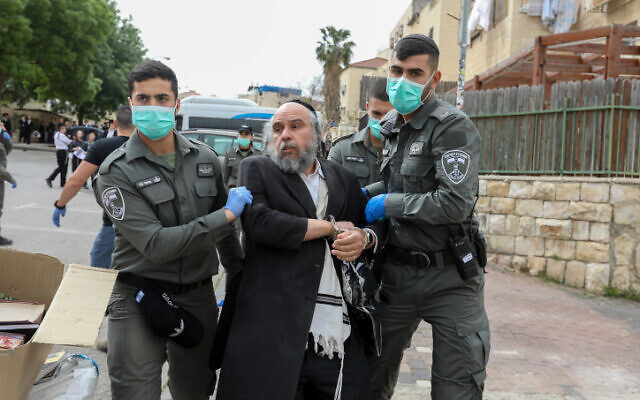Des policiers arrêtent un homme à Beit Shemesh pour faire respecter les règles de distanciation sociale le 31 mars 2020.
(Crédit : Yaakov Lederman/Flash90) Des policiers arrêtent un homme à Beit Shemesh pour faire respecter les règles de distanciation sociale le 31 mars 2020.
(Crédit : Yaakov Lederman/Flash90)