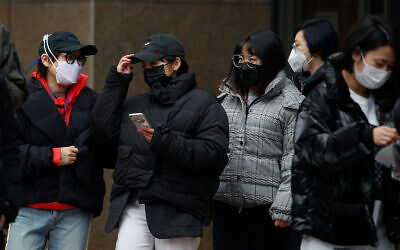 Des employés de bureau portant des masques de protection pendant une pause déjeuner à Pékin, Chine, le 24 février 2020. (AP/Andy Wong)