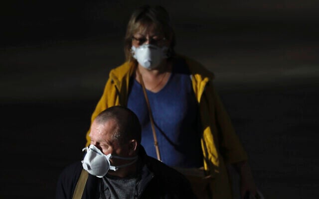 Des passagers portent des masques pour se protéger du coronavirus à l'aéroport Ben Gurion, à proximité de Tel Aviv, en Israël, le dimanche 8 mars 2020. (AP Photo/Ariel Schalit)