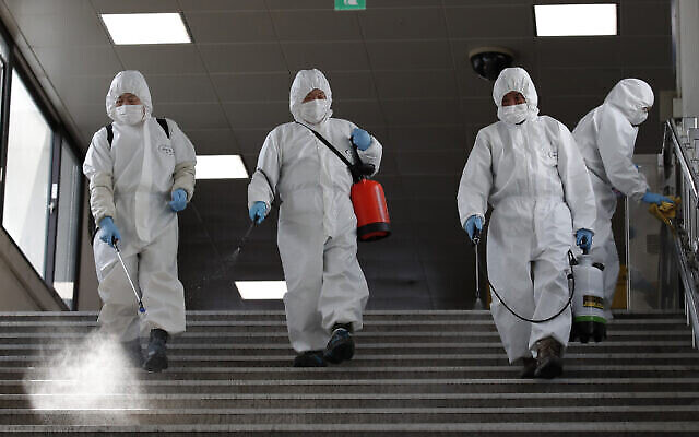 Des employés portant des masques de protection désinfectent par précaution contre le nouveau coronavirus dans une station du métro de Séoul, en Corée du Sud, le vendredi 13 mars 2020. (AP Photo/Lee Jin-man)