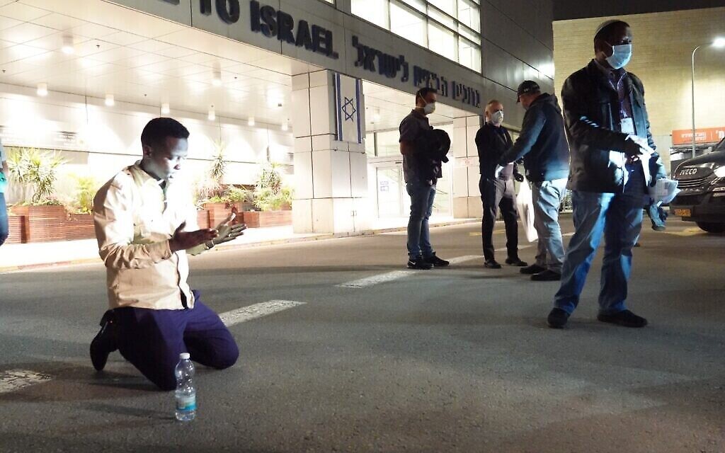 Un immigrant éthiopien s'agenouille peu après son arrivée à l'aéroport Ben Gurion, le 24 mars 2020. (Michael Dimenstein/ GPO)