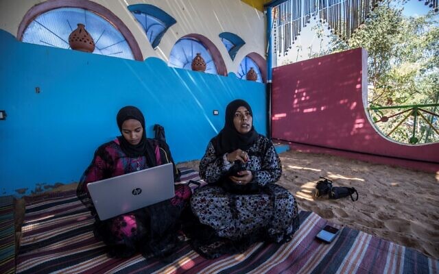 Hafsa Amberkab (R) and Fatma Addar (L), Nubian Egyptian women who compiled a handy dictionary of some 230 words in the Kenzi dialect, speak to an AFP journalist as they show off a Nubian lexical chart in the village of Gharb Suhail, near Aswan in Upper Egypt, some 920 kilometres south of the capital Cairo, on February 3, 2020. - Addar grew up in a Nubian family but as a child was schooled mostly in Arabic -- only hearing her ancestral tongue when spoken by the family elders. Amberkab, an entrepreneur, launched the initiative "Koma Waidi" -- meaning tales from the past -- documenting stories told by elders and collecting dying expressions. According to locals, the Nubian language is unpractised by many after their mass eviction from their ancestral lands to make way for the construction of the Aswan High Dam on the Nile in the 1960s. (Photo by Khaled DESOUKI / AFP)