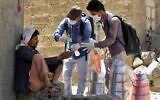Des volontaires yéménites désinfectent les mains d'un homme dans l'un des quartiers pauvres de Sanaa, le 30 mars 2020, en pleine épidémie de COVID-19.
(Crédit : MOHAMMED HUWAIS / AFP)