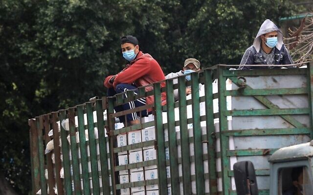 Les employés palestiniens de l'UNRWA, agence d'aide de l'ONU aux réfugiés palestiniens, à l'arrière d'un camion qui livre de l'aide alimentaire à Gaza City, le 31 mars 2020 (Crédit : Mahmud Hams/AFP) Les employés palestiniens de l'UNRWA, agence d'aide de l'ONU aux réfugiés palestiniens, à l'arrière d'un camion qui livre de l'aide alimentaire à Gaza City, le 31 mars 2020 (Crédit : Mahmud Hams/AFP)
