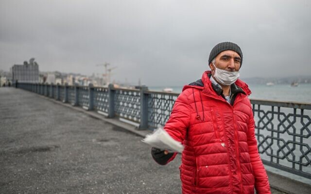 Un vendeur tente de vendre des masques de protection sur le pont vide de Galata le 1 avril 2020 à Istanbul, après que des responsables turcs ont appelé les citoyens à rester à la maison et à respecter les règles de distanciation sociale. (Crédit : Ozan KOSE / AFP) Un vendeur tente de vendre des masques de protection sur le pont vide de Galata le 1 avril 2020 à Istanbul, après que des responsables turcs ont appelé les citoyens à rester à la maison et à respecter les règles de distanciation sociale. (Crédit : Ozan KOSE / AFP)