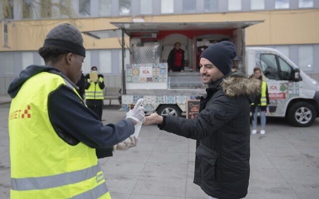 Un bénévole propose du désinfectant pour les mains lors d'une campagne d'information en plusieurs langues sur la nouvelle pandémie de coronavirus COVID-19, dans la banlieue de Tensta à Stockholm, qui abrite un grand nombre d'immigrants, le 12 avril 2020. (Crédit : ALI LORESTANI / TT Agence de presse / AFP) / Suède OUT)