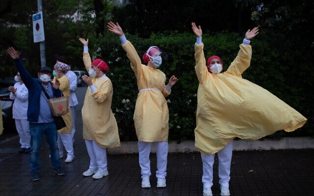 Des personnels médicaux portant des masques et des combinaisons de protection lors des applaudissements à l'extérieur de l'hôpital de Barcelone, le 13 avril 2020. (Crédit : Josep LAGO / AFP)