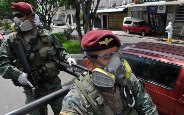 Des soldats patrouillent dans les rues du quartier Cisne 2, le long des rives de la rivière Estero Salado, à Guayaquil, en Équateur, le 14 avril 2020 dans le cadre de la pandémie de coronavirus. (Crédit : Jose SANCHEZ / AFP)
