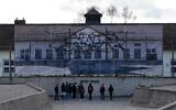 Des visiteurs se tiennent devant le Mémorial international de l'ancien camp de concentration de Dachau, dans le sud de l'Allemagne, le 09 décembre 2019. - L'ancien camp de Dachau, construit en 1933 et qui a servi de modèle à tous les autres camps de concentration en Europe, a été mis à profit par le gouvernement de Bavière, la région dans laquelle il est situé. (Crédit : Christof STACHE / AFP)