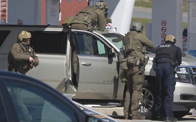 Des agents de la Gendarmerie royale du Canada face au suspect d'une fusillade dans une station-service à Enfield, en Nouvelle-Écosse, le dimanche 19 avril 2020. (Crédit : Tim Krochak / The Canadian Press via AP)