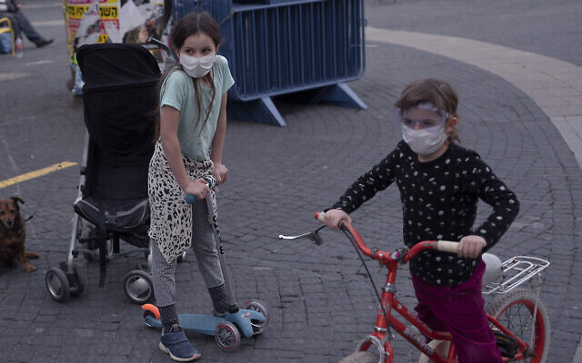 Des enfants portent des masques en pleine pandémie de coronavirus, à Tel Aviv, le 24 mars 2020. (Crédit : AP Photo/Oded Balilty) Des enfants portent des masques en pleine pandémie de coronavirus, à Tel Aviv, le 24 mars 2020. (Crédit : AP Photo/Oded Balilty)