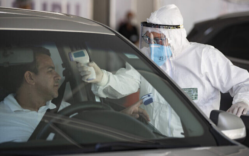 Le personnel médical contrôle les personnes à l'intérieur de leur voiture pour savoir si elles présentent des symptômes du COVID-19 à Guarulhos, dans la banlieue de Sao Paulo, au Brésil, le lundi 30 mars 2020. (Crédit : AP Photo/Andre Penner)