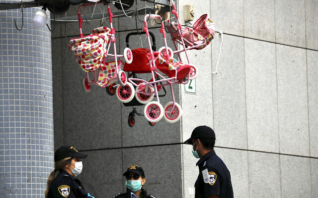 Des policiers masqués bloquent l'entrée d'un centre commercial à Bnei Brak le 31 mars 2020. (Crédit : AP/Ariel Schalit)