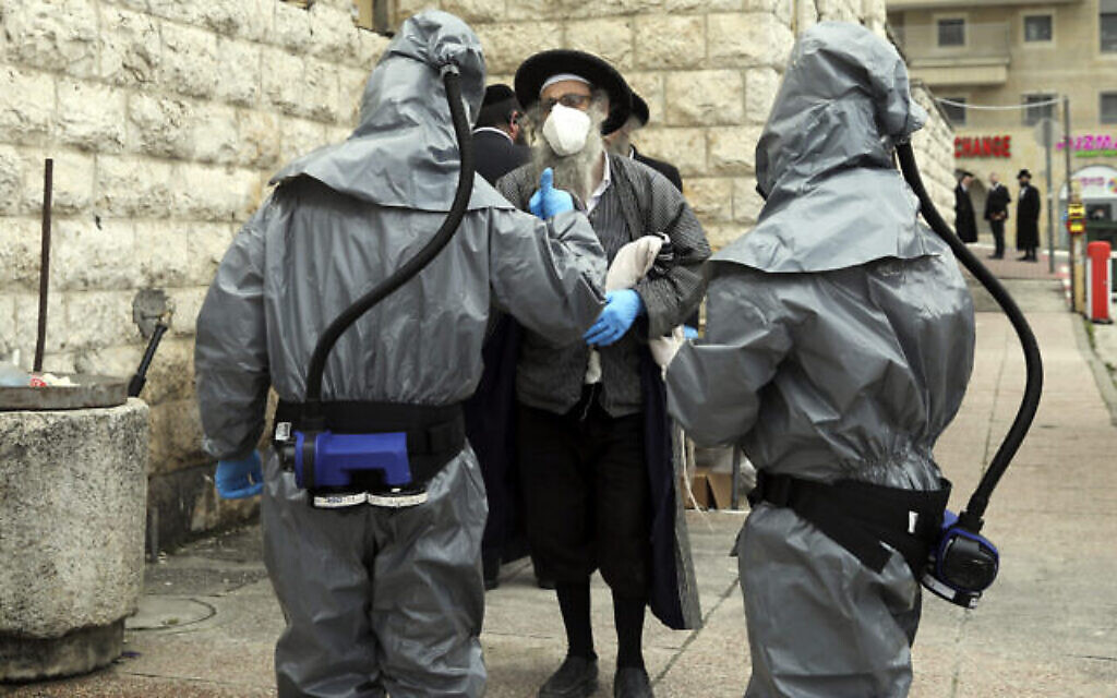 Un juif orthodoxe s'entretient avec des membres de Hevra Kadisha venus enlever le corps d'une personne décédée du coronavirus à Jérusalem, le 1er avril 2020. (Crédit : AP Photo/Mahmoud Illean) Un juif orthodoxe s'entretient avec des membres de Hevra Kadisha venus enlever le corps d'une personne décédée du coronavirus à Jérusalem, le 1er avril 2020. (Crédit : AP Photo/Mahmoud Illean)
