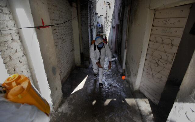 Des bénévoles d'une organisation caritative désinfectent les allées d'un quartier pauvre afin d'endiguer la propagation du virus à Islamabad au Pakistan, le mercredi 15 avril 2020. (AP Photo/Anjum Naveed)