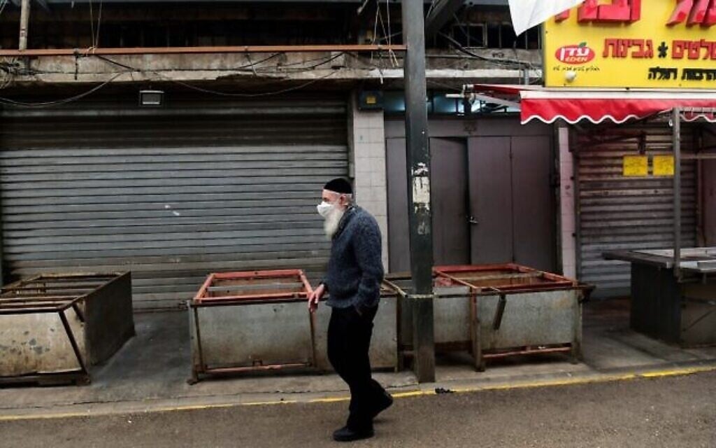 Photo d'illustration : Un homme portant un masque facial marche dans le marché vide de Ramla, le 23 mars 2020 (Crédit : Flash90)