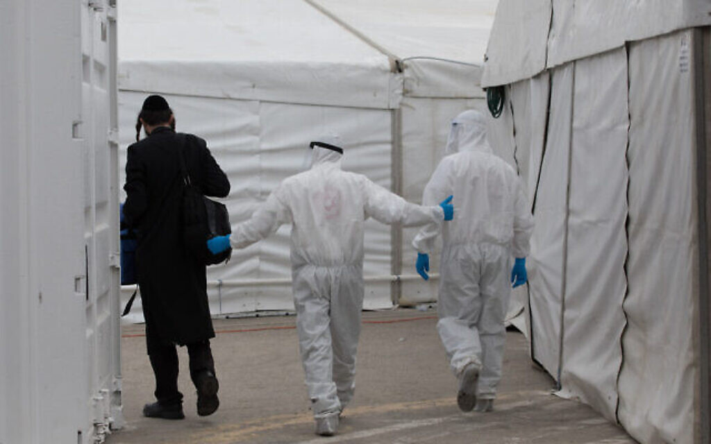 Des employés du Magen David Adom et une équipe médicale de Shaare Tzedek, portant des équipements de protection contre le coronavirus, aux abords de la nouvelle unité de l'hôpital Shaare Zedek à Jérusalem, le 2 avril 2020 (Crédit :  Nati Shohat/Flash90)