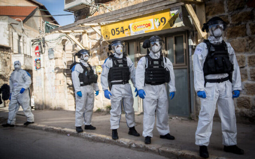 Des agents de police israéliens en combinaison de protection dans le quartier ultra-orthodoxe de Mea Sharim à Jérusalem, le 6 avril 2020. (Crédit : Yonatan Sindel/Flash90)