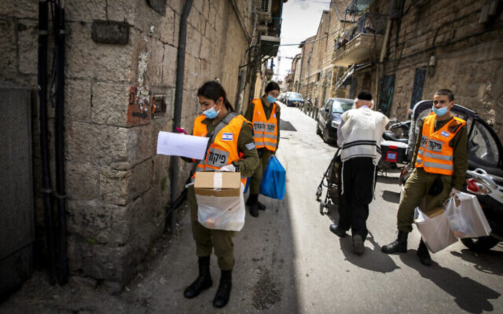 Des soldats du commandement intérieur distribuent des colis alimentaires aux personnes âgées obligées de rester confinées en raison de la crise du coronavirus avant la fête juive de Pessah, dans un quartier haredim de Jérusalem, le 7 avril 2020 (Crédit : Olivier Fitoussi/Flash90)