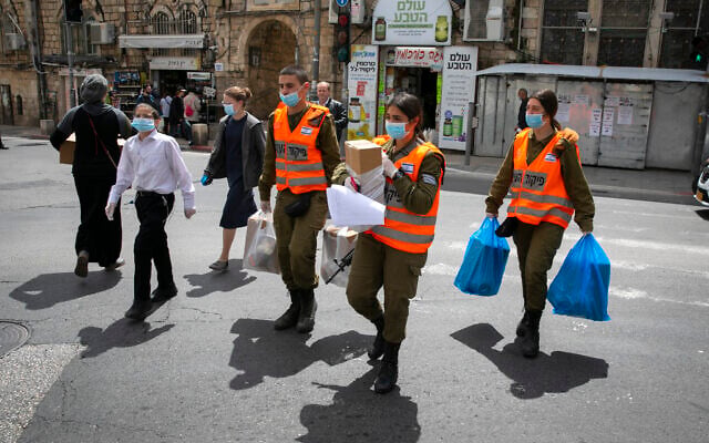Des soldats du commandement intérieur distribuent des colis alimentaires aux personnes âgées obligées de rester confinées en raison de la crise du coronavirus avant la fête juive de Pessah, dans un quartier haredim de Jérusalem, le 7 avril 2020 (Crédit : Olivier Fitoussi/Flash90) Des soldats du commandement intérieur distribuent des colis alimentaires aux personnes âgées obligées de rester confinées en raison de la crise du coronavirus avant la fête juive de Pessah, dans un quartier haredim de Jérusalem, le 7 avril 2020 (Crédit : Olivier Fitoussi/Flash90)