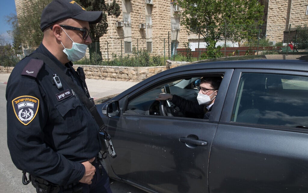 Un officier de la police israélienne à un poste de contrôle temporaire à l'entrée de Neve Yaakov, à Jérusalem, le 12 avril 2020. (Crédit : Nati Shohat / Flash90) Un officier de la police israélienne à un poste de contrôle temporaire à l'entrée de Neve Yaakov, à Jérusalem, le 12 avril 2020. (Crédit : Nati Shohat / Flash90)