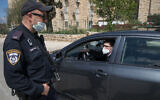 Un officier de la police israélienne à un poste de contrôle temporaire à l'entrée de Neve Yaakov, à Jérusalem, le 12 avril 2020. (Crédit : Nati Shohat / Flash90)