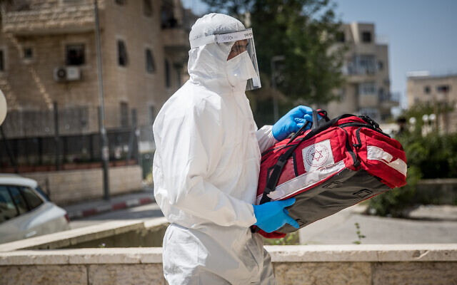 Des employés du Magen David Adom en combinaison de protection contre le coronavirus se rendent chez un malade présumé à Jérusalem, le 14 avril 2020 (Crédit : Yonatan Sindel/Flash90) Des employés du Magen David Adom en combinaison de protection contre le coronavirus se rendent chez un malade présumé à Jérusalem, le 14 avril 2020 (Crédit : Yonatan Sindel/Flash90)