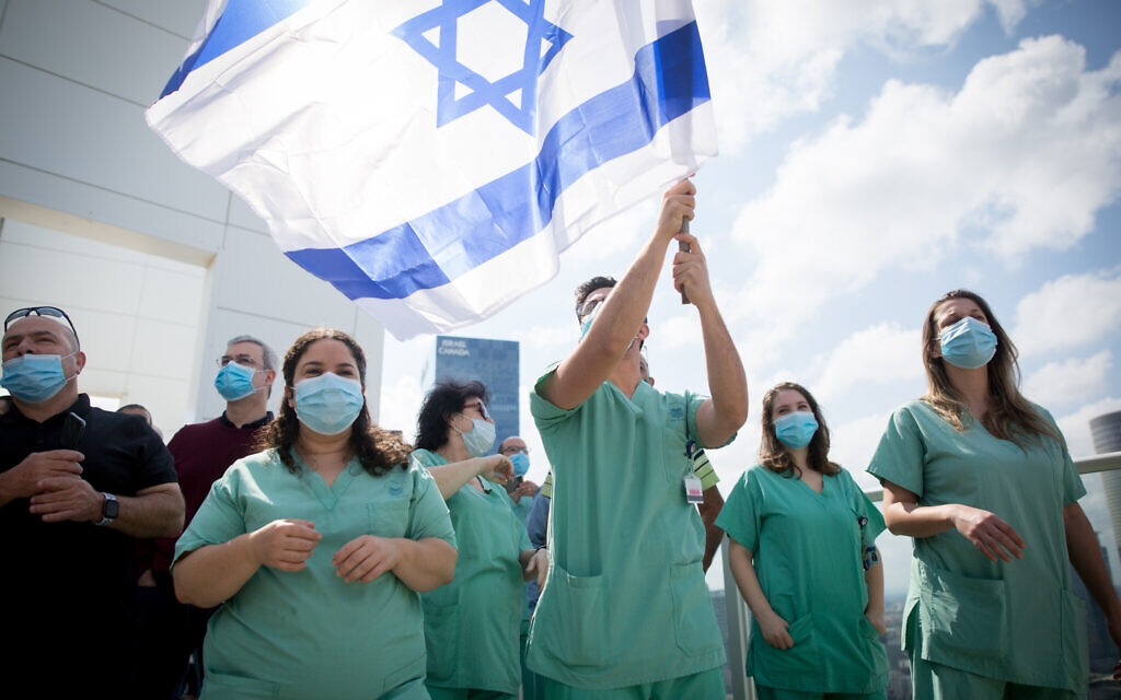 Le personnel médical acclame une équipe de voltige de l'armée de l'air israélienne survolant l'hôpital Ichilov à Tel Aviv, lors du 72e anniversaire de l'indépendance d'Israël, Yom HaAtsmaout, le 29 avril 2020. (Miriam Alster/Flash90) Le personnel médical acclame une équipe de voltige de l'armée de l'air israélienne survolant l'hôpital Ichilov à Tel Aviv, lors du 72e anniversaire de l'indépendance d'Israël, Yom HaAtsmaout, le 29 avril 2020. (Miriam Alster/Flash90)