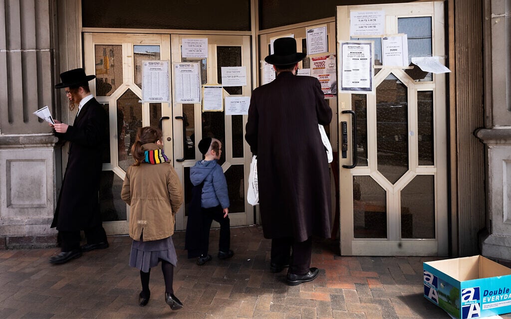 Un homme s'arrête pour lire des annonces affichées sur les portes d'une synagogue dans le quartier de Williamsburg à Brooklyn, New York, le 7 avril 2020. (Crédit : AP/Mark Lennihan) Un homme s'arrête pour lire des annonces affichées sur les portes d'une synagogue dans le quartier de Williamsburg à Brooklyn, New York, le 7 avril 2020. (Crédit : AP/Mark Lennihan)