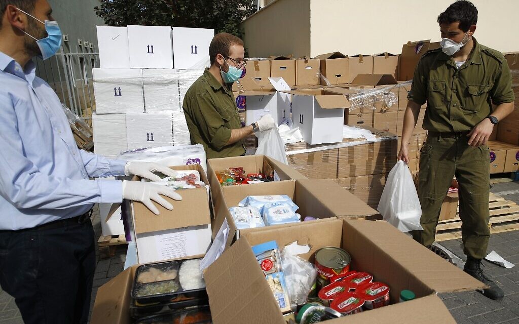 Des soldat israéliens portent des cartons de nourritures et d'autres produits de première nécessité qu'ils vont distribuer aux seniors placé à l'isolement dans la ville côtière de Bat Yam, le 7 avril 2020. (Photo par JACK GUEZ / AFP) Des soldat israéliens portent des cartons de nourritures et d'autres produits de première nécessité qu'ils vont distribuer aux seniors placé à l'isolement dans la ville côtière de Bat Yam, le 7 avril 2020. (Photo par JACK GUEZ / AFP)
