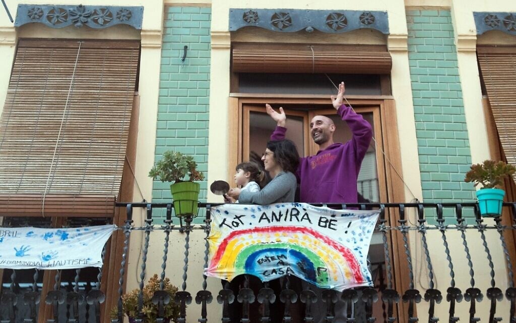 Une famille applaudit depuis son balcon, avec une banderole où l'on peut lire "Tout ira bien" le 9 avril 2020 à Valence en Espagne, lors du confinement national pour lutter contre la propagation du COVID-19. (Photo par Jose Jordan / AFP)