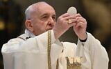 Le Pape François tient une hostie en célébrant l'Eucharistie lors de la messe du dimanche de Pâques le 12 avril 2020, derrière les portes fermées de la Basilique Saint-Pierre au Vatican. (Crédit : Andreas Solaro/Pool/AFP)