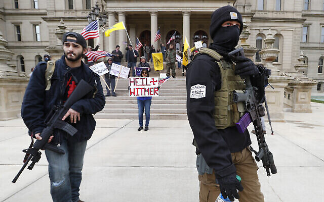 Des manifestants portent des armes devant les marches de bâtiment du Capitol de l'Etat du Michigan à Lansing, aux États-Unis, le 15 avril 2020. (Crédit : AP/Paul Sancya) Des manifestants portent des armes devant les marches de bâtiment du Capitol de l'Etat du Michigan à Lansing, aux États-Unis, le 15 avril 2020. (Crédit : AP/Paul Sancya)