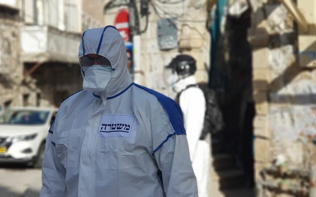 La police israélienne, portant des vêtements de protection, est dans le quartier de Mea Sherim de Jérusalem pour arrêter un homme contaminé au COVID-19 qui a enfreint les règles de quarantaine, le 6 avril 2020. (Crédit : police israélienne)