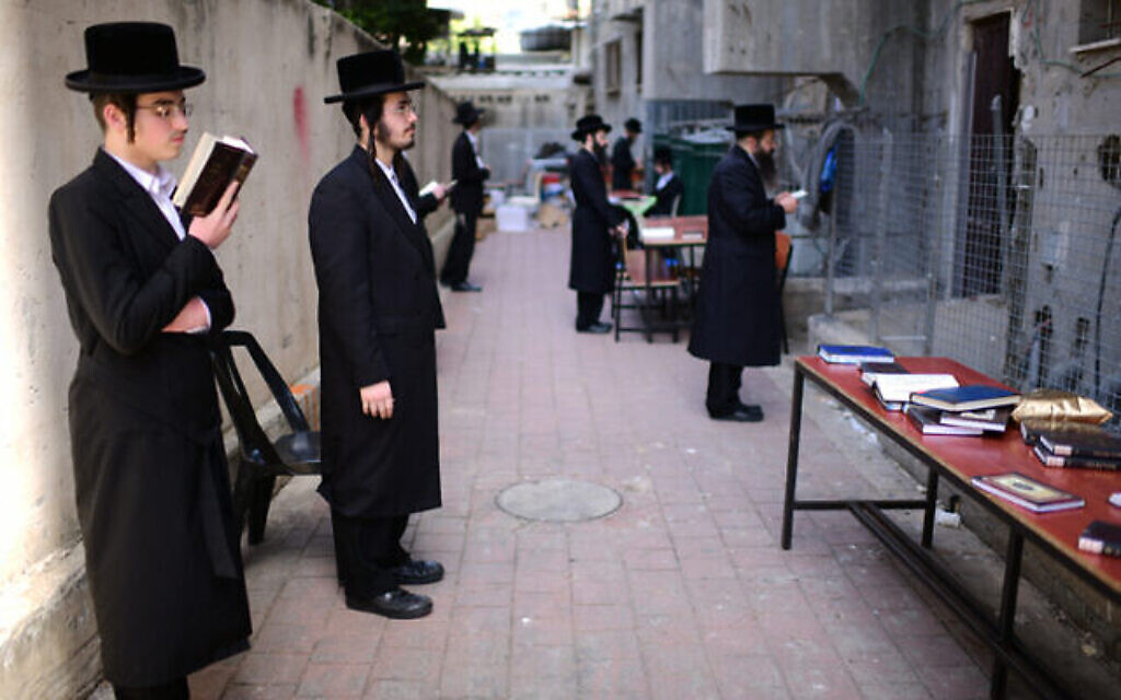 Des hommes juifs ultra-orthodoxes prient devant une yeshiva fermée dans la ville de Bnei Brak, le 26 mars 2020.
(Tomer Neuberg/Flash90) Des hommes juifs ultra-orthodoxes prient devant une yeshiva fermée dans la ville de Bnei Brak, le 26 mars 2020.
(Tomer Neuberg/Flash90)