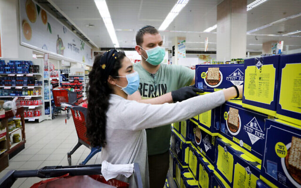 Des gens portent des masques pour se protéger du coronavirus alors qu'ils achètent du matzah, un pain non levé traditionnellement consommé pour Pessah, dans un supermarché de Jérusalem, le 31 mars 2020.
(Yossi Zamir/Flash90)